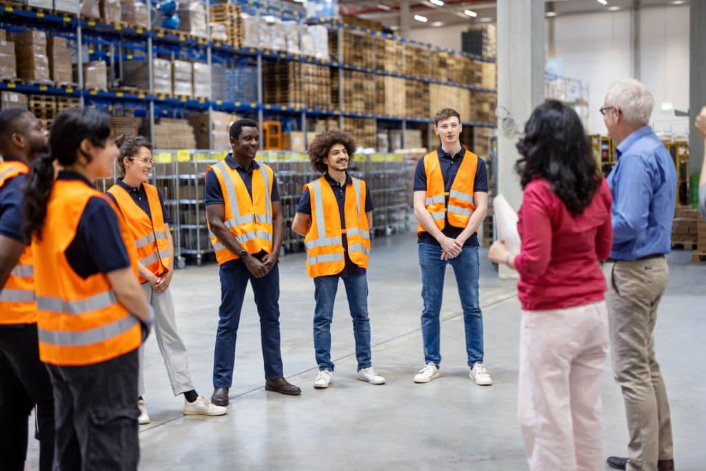Warehouse team meeting with a supervisor inside a distribution facility